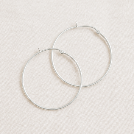 Pair of silver hoop earrings on a light beige background