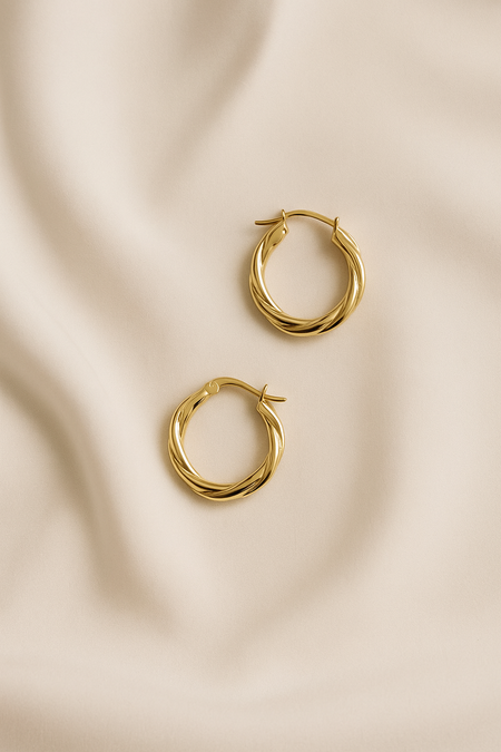 Gold hoop earrings on a beige fabric background