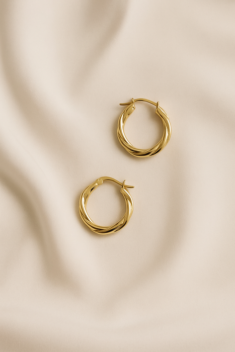 Gold hoop earrings on a beige fabric background