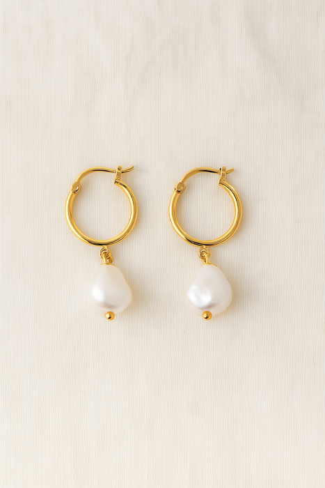 Gold hoop earrings with pearl drops on a beige background
