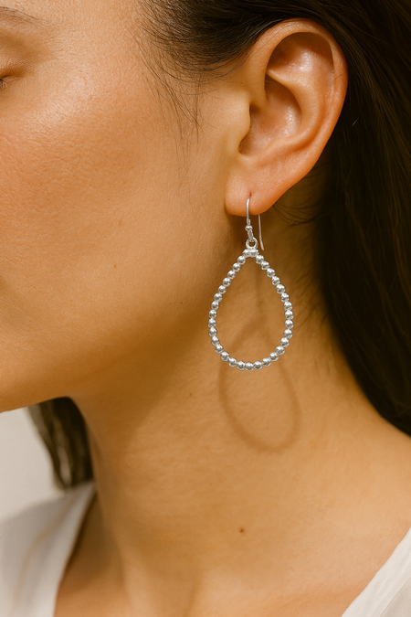 Close-up of a person wearing a silver hoop earring.